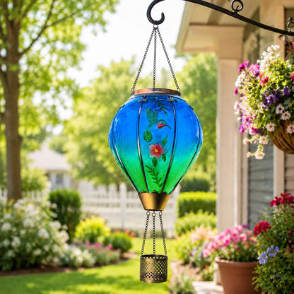 Hummingbird and flower hot air balloon solar lantern hanging beside a colorful garden porch